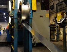 A coil of sheet metal being fed into machinery