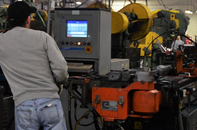 An engineer operating a steel tube fabrication machine