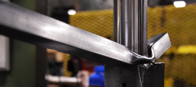 Metal tubing undergoing intense compression testing