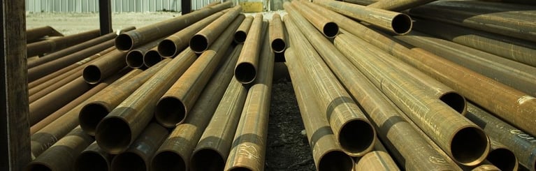 A stack of metal tubes stored in a yard